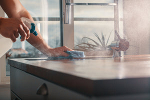 Summer Holiday Cleaning Checklist: Tips to Keep Your Kitchen Safe: Spraying kitchen counter with spray bottle