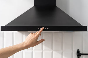 person pressing a button on a range hood