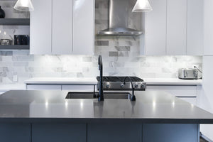 Wall mount range hood comparison from hauslane image showing a stainless steel wall mount range hood over the stove in a kitchen with white cabinets and black countertop