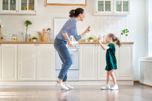 How to Clean Greasy Kitchen Cabinets Based on Material. Girl and mom dancing in a clean kitchen. Learn how to properly clean greasy kitchen cabinets without damaging them.