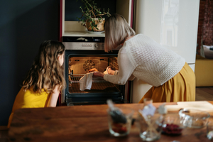 Mother daughter pulling food out of the oven