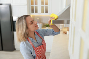 woman cleaning stainless steel range hood with soft rag